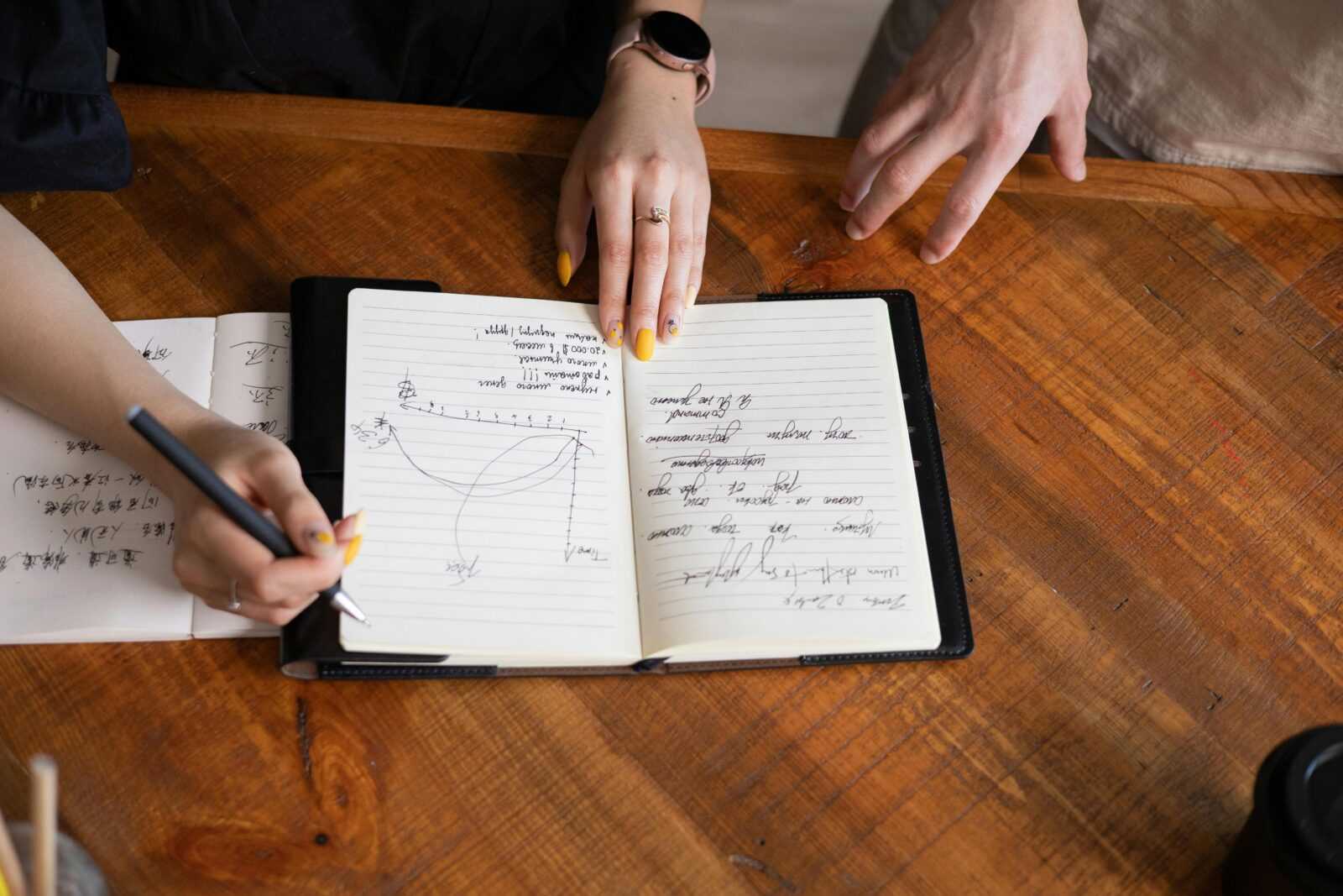 Person Holding White Paper on Brown Wooden Table